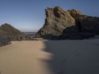 the sandy beach has a rock formation near it, as seen in this image from below