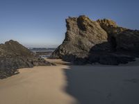 the sandy beach has a rock formation near it, as seen in this image from below