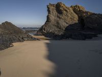 the sandy beach has a rock formation near it, as seen in this image from below