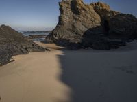 the sandy beach has a rock formation near it, as seen in this image from below