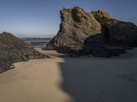 the sandy beach has a rock formation near it, as seen in this image from below