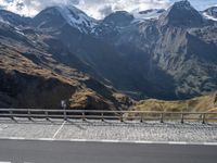 a person riding a bike through the mountains near a bridge and cars parked on a road