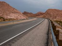 the paved highway has several curves along the middle of it on both sides of it is a few hills