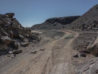 a road with a small car parked on top of it surrounded by rock and dirt