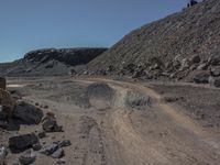 a road with a small car parked on top of it surrounded by rock and dirt