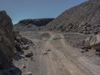 a road with a small car parked on top of it surrounded by rock and dirt