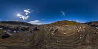 a large hill that has rocks on it and dirt on top of it and clouds