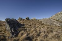 rocks on a mountain, and grass in the foreground and sky in the background