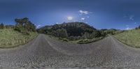 the view from a fisheye lens looking up at a road with mountains in the background