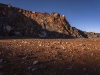 the view of mountains in the distance from a barren area with dirt and rocks strewn across the mountain