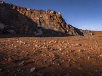 the view of mountains in the distance from a barren area with dirt and rocks strewn across the mountain