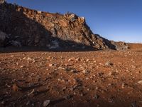 the view of mountains in the distance from a barren area with dirt and rocks strewn across the mountain