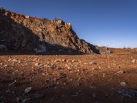 the view of mountains in the distance from a barren area with dirt and rocks strewn across the mountain