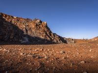 the view of mountains in the distance from a barren area with dirt and rocks strewn across the mountain