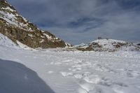 snow and rocks make for a steep incline on a clear day of blue skies and clouds