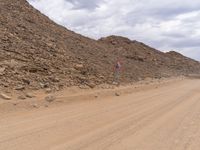 a small vehicle traveling across a barren road between some large rocks and boulders on one side