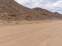 a small vehicle traveling across a barren road between some large rocks and boulders on one side