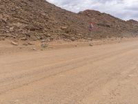 a small vehicle traveling across a barren road between some large rocks and boulders on one side