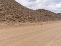 a small vehicle traveling across a barren road between some large rocks and boulders on one side