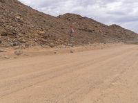 a small vehicle traveling across a barren road between some large rocks and boulders on one side