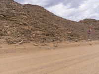 a small vehicle traveling across a barren road between some large rocks and boulders on one side