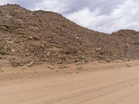 a small vehicle traveling across a barren road between some large rocks and boulders on one side