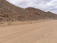 a small vehicle traveling across a barren road between some large rocks and boulders on one side