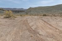 this is an image of dirt road near a cliff line area with a desert background