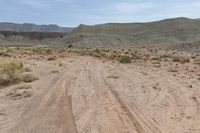 this is an image of dirt road near a cliff line area with a desert background