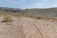 this is an image of dirt road near a cliff line area with a desert background