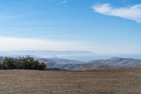 a lone red stop sign stands in the middle of a barren terrain area with mountains in the distance