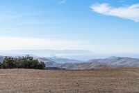 a lone red stop sign stands in the middle of a barren terrain area with mountains in the distance