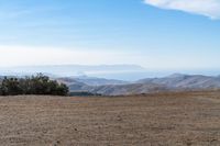 a lone red stop sign stands in the middle of a barren terrain area with mountains in the distance