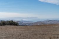 a lone red stop sign stands in the middle of a barren terrain area with mountains in the distance