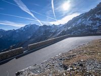 the man is riding on his bike down the road with mountains in the background and blue sky