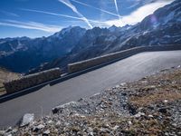 the man is riding on his bike down the road with mountains in the background and blue sky