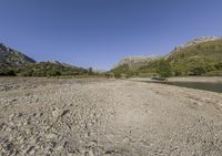 there is a very large body of water with mountains in the background next to a grassy plain