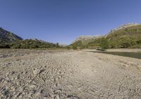 there is a very large body of water with mountains in the background next to a grassy plain