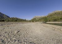 there is a very large body of water with mountains in the background next to a grassy plain