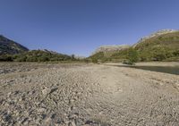 there is a very large body of water with mountains in the background next to a grassy plain