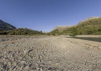 there is a very large body of water with mountains in the background next to a grassy plain