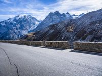 mountains in the distance on an empty highway near a stone fence with a bike leaning up against it