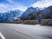 mountains in the distance on an empty highway near a stone fence with a bike leaning up against it