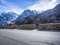 mountains in the distance on an empty highway near a stone fence with a bike leaning up against it