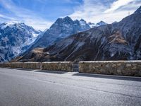 mountains in the distance on an empty highway near a stone fence with a bike leaning up against it