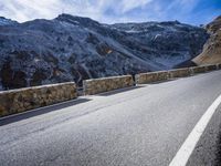 a road running between two mountains with a stone wall and fence in the center of it