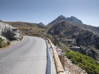 an asphalt mountain side near the road in the desert with steep hills around it and a mountain top to one side