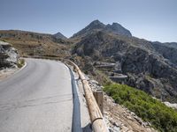 an asphalt mountain side near the road in the desert with steep hills around it and a mountain top to one side