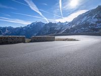 a paved mountain area with a road winding to the side with snow capped mountains in the background