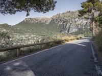 a paved road running beside a mountain on a sunny day in the mountains near marseille